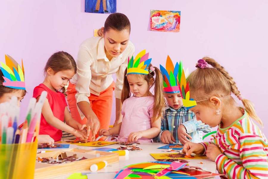 Beautiful young teacher woman show little children boys and girls how to make glue and draw craft image in preschool class